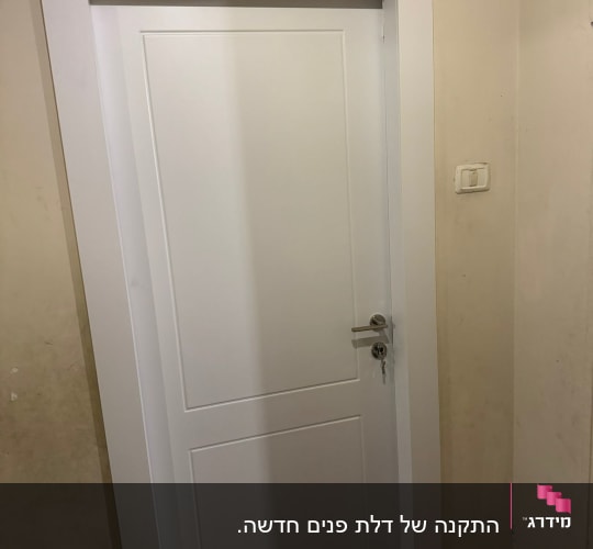 דלת לבנה עם ידית כסופה על קיר בהיר